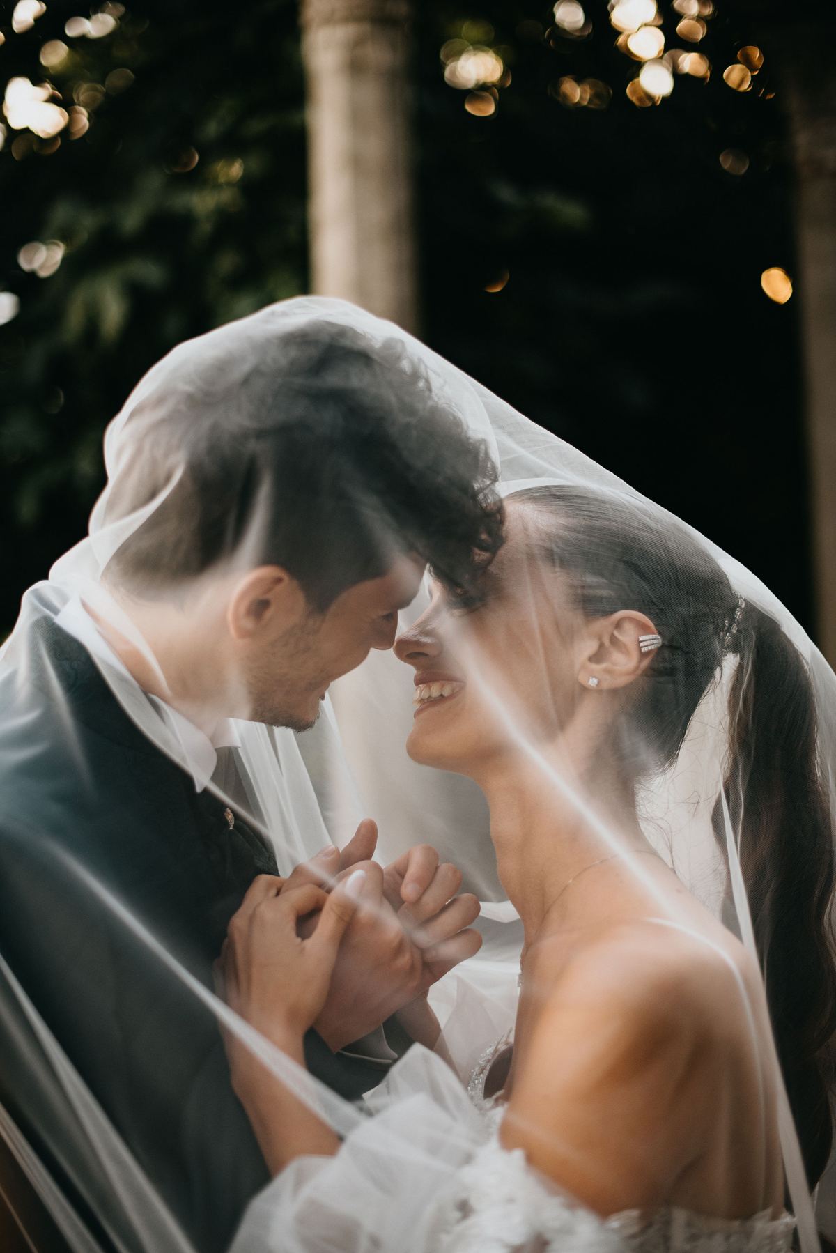 Sposa che ride sotto il velo abbracciata allo sposo